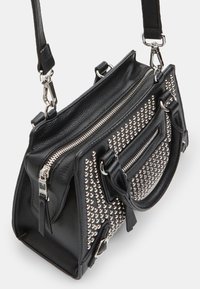 Bolso de cuero negro con tachuelas plateadas, dos asas y una correa ajustable. Cuenta con un compartimento principal con cremallera y un bolsillo frontal.
