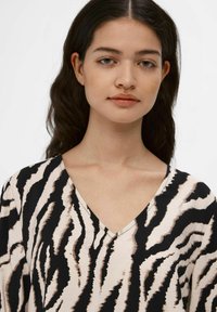 V-hals bluse med et zebra stribe mønster i sort og beige. Fremstillet af blødt stof med en glat overflade og en flydende design.