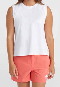 Vit ärmlös topp i bomull med rund halsringning. Kombinerad med ljusrosa shorts som har en minimalistisk logotyp på sidan.