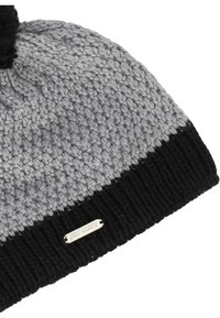 Stickad mössa i grått och svart, med ett texturerat mönster, en vikt ribbad kant och en metallisk logotag på sidan.