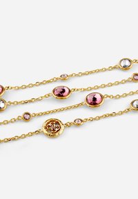 Gold-toned chain necklace featuring pink and clear gemstones of various sizes in circular settings, with an intricate round metallic detail.