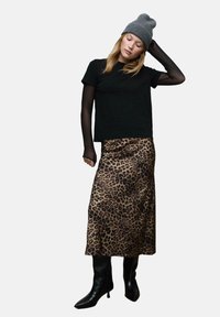 Czarna koszulka z krótkim rękawem, nałożona na koszulę z długim rękawem z siateczki, w połączeniu z midi spódnicą w panterkę i czarnymi kozaczkami na obcasie do kolan.