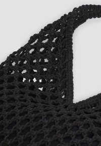 Zwarte gebreide tas met een gaasontwerp, voorzien van een gestructureerde geweven handgreep en een volledig zwarte voering.