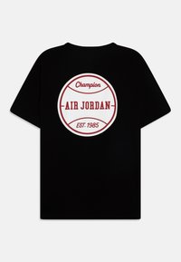 Černé bavlněné tričko s kulatým bílým a červeným grafickým motivem s nápisy "Champion", "AIR JORDAN" a "EST. 1985". Krátké rukávy, klasický výstřih.