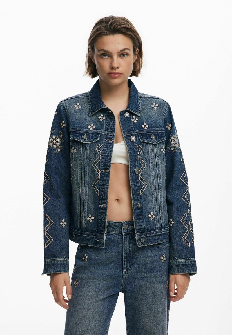 Jeansjacka med blommig broderi, figurnära design, mörkblå färg, silverdetaljer, med zigzagmönster på ärmar och kropp.