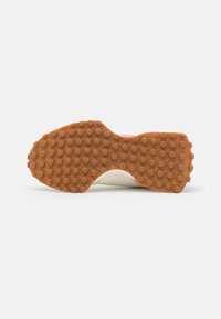 Sneakersula i ljusbrun gummi med upphöjda cirkulära mönster. Har en slät krämfärgad övre del som sträcker sig runt kanten.