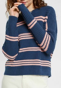 Granatowy sweter dzianinowy w różowe poziome paski, z prążkowaną strukturą, długimi rękawami i luźnym krojem.