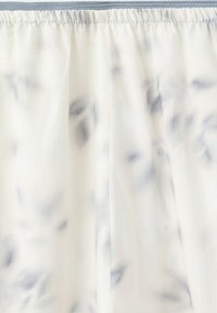 Tissu tie-dye gris clair et blanc avec une ceinture élastique froncée et une couture verticale centrale.