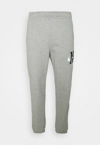 Ljust grå sweatpants med elastisk midja och muddar, med en liten svartvit logotyp på höger lår.