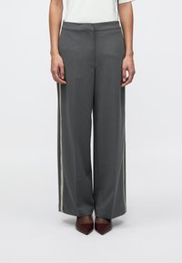 Γκρι παντελόνι με φαρδιά γραμμή κατασκευασμένο από λείο ύφασμα, με μπεζ λωρίδες στο πλάι με λεπτομέρειες κειμένου, συνδυασμένο με μπορντό γόβες με μυτερή μύτη.