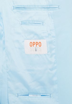 Svetlomodrá tkanina s etiketou „OPPO SUITS“ v oranžovej a šedej farbe, so skúmavkami na dvoch vnútorných vreckách.