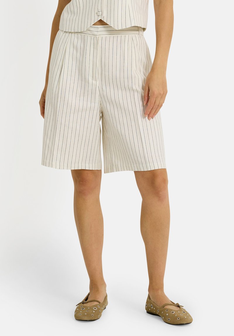 Shorts blancs arrivant au genou avec des rayures verticales bleu et noir, présentant un design plissé et une taille lisse.