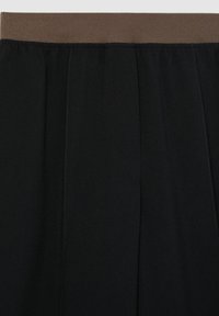 Pantaloni neri con una cintura testurizzata marrone. Presentano cuciture verticali e una finitura in tessuto liscia. Nessuna tasca visibile.