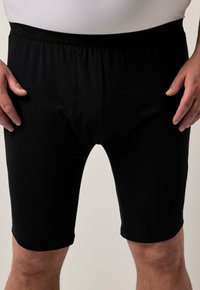 Shorts en mélange de coton noir avec une taille élastique, présentant une texture lisse et une coupe ajustée, se terminant au-dessus du genou.
