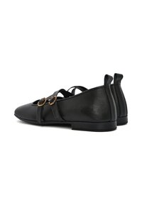 Scarpe in pelle nera con punta arrotondata, due fascette decorative e accessori in oro. Finitura opaca e texture ruvida. Suola piatta e tacco posteriore.