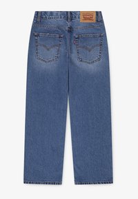 Μπλε τζιν παντελόνι με ίσια γραμμή, διαθέτοντας δύο πίσω τσέπες και δερμάτινη ετικέτα στη μέση. Φθαρμένη υφή και λεπτομέρειες ραφής.