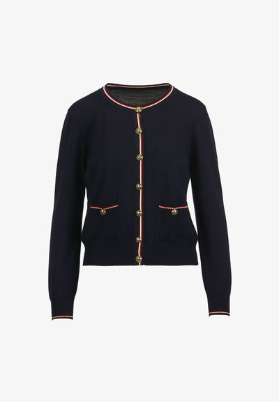 Marineblauer Cardigan mit goldenen Knöpfen, rotem und weißem Besatz entlang der Knopfleiste und der Manschetten, ausgestattet mit zwei Fronttaschen mit Rippenstruktur.