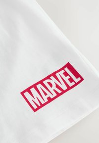 Fehér pamut póló, amelyen egy merész piros téglalap alakú logó olvasható, rajta nagybetűs "MARVEL" felirattal. Sima textúrájú, normál fazonú.