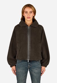 Tumedast hall nahkjope, millel on lukuga esikülg, üle mõõtmega krae, elastsed mansetid ja küljetaskud. Pehme tekstuur ja mugav lõige.