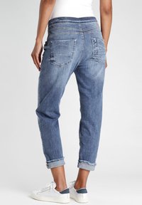 Vaaleansiniset farkut rennoilla mitoituksilla, joissa on käännetyt lahkeet, takataskut ja pehmeä vyötärö. Klassinen viisi-taskuinen muotoilu.