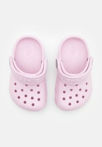Rosa Crocs-tofflor av lätt plast med ventilationshål, texturerad innersula och en bakre rem för säker passform.