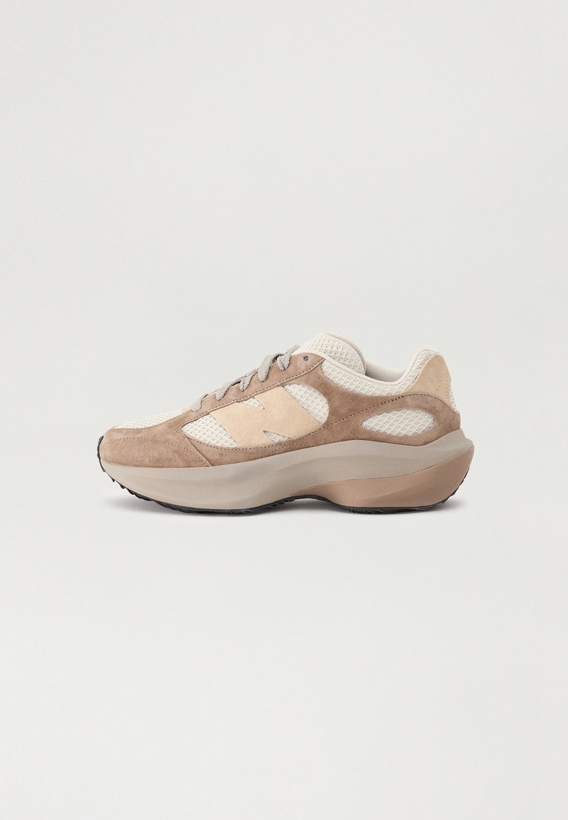 Baskets beige et marron clair avec dessus en mesh et daim, fermeture à lacets devant, semelle épaisse et rembourrée, présentées sur un fond gris clair uni.