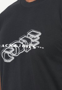 Tricou negru din bumbac cu text grafic alb într-un stil stratificat, 3D, purtând numele brandului "Jack & Jones" și anul "1990".