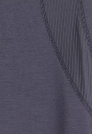 Close-up van donkergrijs stof met gladde en geribbelde textuursecties gescheiden door zichtbare dubbelgestikte naden.