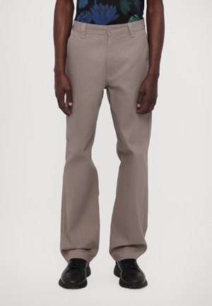 Gray cotton trousers with a straight fit, featuring a button closure and two side pockets. Paired with black athletic shoes.