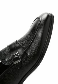 Zwarte leren schoen met een gestructureerd oppervlak, een afgeronde neusontwerp, decoratieve gespaccent en een slanke zwarte zool.