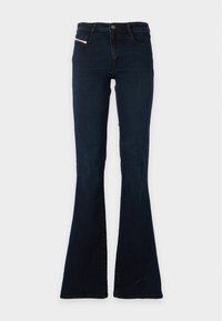 Jean bleu foncé taille haute avec jambe évasée, poches avant et fermeture par bouton et zip.