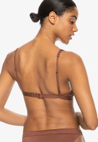 Hnedý bikiny top s tenkými nastaviteľnými ramienkami, háčikovým zapínaním na zadnej strane a hladkým, elastickým materiálom pre pohodlie a dobré padnutie.