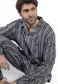 Conjunto de pijama a rayas azul y beige hecho de tejido ligero; incluye una camiseta con botones, bolsillo y pantalones de corte relajado.
