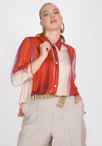 Multicolore gestreepte blouse met een kraag, in tinten oranje, roze en crème, gecombineerd met beige hoge taille broeken en een geweven riem.