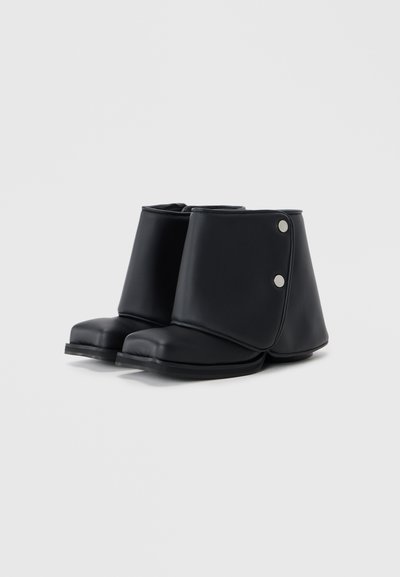 Bocanci negri până la gleznă, din material sintetic neted, cu vârf pătrat, design pliat și capse argintii pe lateral.