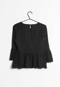 Top in pizzo nero con maniche a tre quarti, orlo a peplum e apertura a chiave sul retro. Caratterizzato da motivi floreali e dettagli testurizzati.