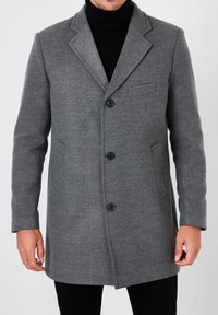 Abrigo de lana gris con cuello con muesca, un solo bolsillo y seis botones negros, con un corte recto y tejido texturizado.