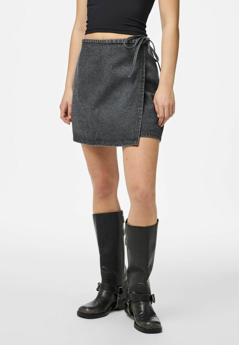 Tamsiai pilkos džinsinės mini sijono su pervyniojimo dizainu, reguliuojamu raiščiu juosmenyje ir matomomis siuvimo detalėmis. Derinama su juodomis iki kelių aukštakulnėmis.