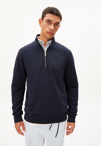 Diepblauwe pullover sweatshirt met een halve rits op de kraag, ribgebreide boorden en onderrand, met een klein blauw logo op de linkerborst. Van zacht katoenmix stof.