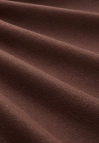 Brauner Stoff mit einer glatten Textur, der weiche Falten und eine gleichmäßige Farbe aufweist. Ideal für verschiedene Textilanwendungen.