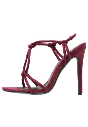 Bordeauxrode suède stiletto sandaal met meerdere geknoopte bandjes en een hoge hak, zijaanzicht op een witte achtergrond.