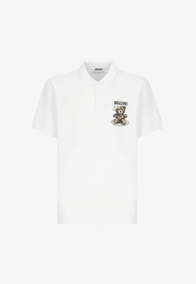 Maglietta polo bianca con grafica di un orsetto marrone e testo "Moschino" sul lato sinistro del petto, dotata di un colletto e di una chiusura a tre bottoni.