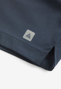 Pantaloncini sportivi blu navy realizzati in tessuto liscio, con un piccolo logo triangolare di colore grigio chiaro e dettagli traforati all'orlo.