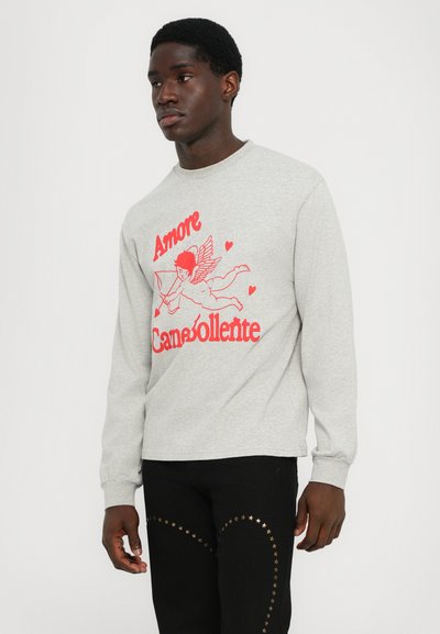 Gray long-sleeve sweatshirt featuring a red graphic of a cherub and text saying "Amore Canebollente." Paired with black pants accented with gold stars.