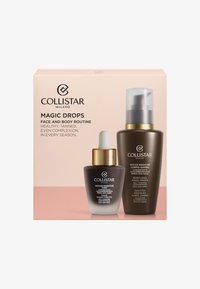 Collistar Magic Drops-setet inkluderar en mörk glasdropperflaska med ett gyllene lock och en brun flaska med pump, förpackad i en pastellfärgad låda.