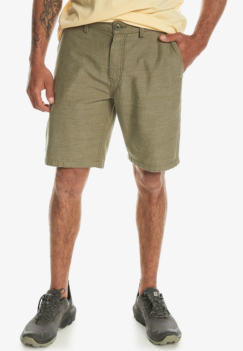 Olivenfarvede shorts lavet af struktureret stof, med frontlukning med knap, bæltesløjfer og skrå lommer på hver side.