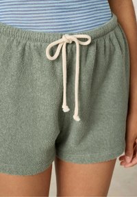 Shorts in spugna verde con vita elastica, cordoncino crema e orlo arrotondato. Texture morbida e design casual.