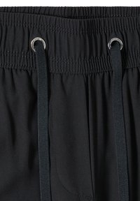 Ceinture élastique noire avec des cordons noirs passés à travers des œillets argentés sur un pantalon ou un short en tissu noir.