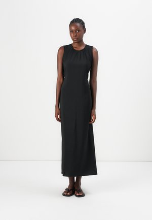 Maxi dress nera senza maniche con scollo rotondo, texture liscia e vestibilità comoda, abbinata a sandali flip-flop neri.