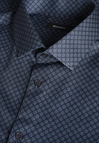 Camisa de botones azul marino con un patrón floral repetitivo en azul claro. Tejido suave con un cuello estándar y botones negros.